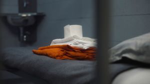 Inmate puts orange prison uniform, bath towel and toilet paper on bed