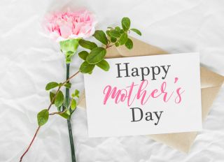 craft envelope, white sheet of paper, one pink carnation and green leaves, inscription text happy mother s day, holiday and sweet wishes concept