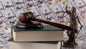 Themis figure and a judge's gavel against the background of $100 bills