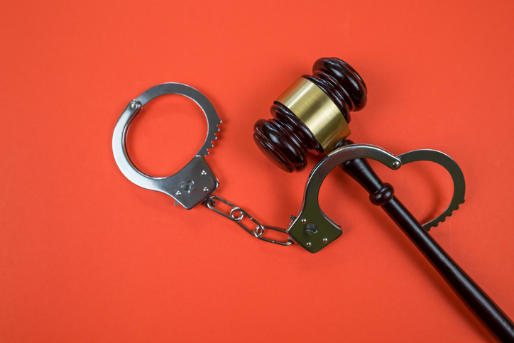 judge gavel with handcuffs on orange background