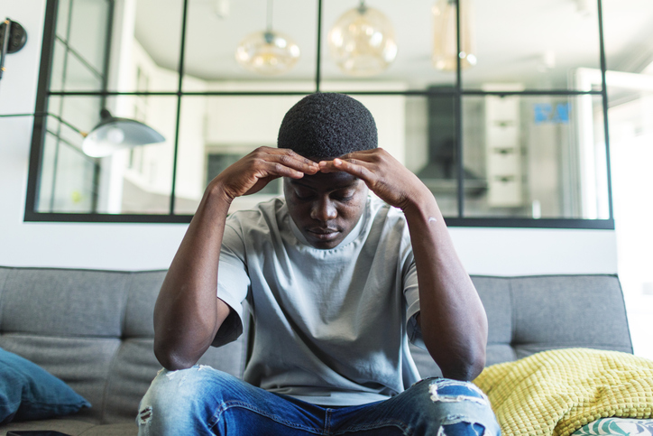 Depressed young man sitting at home alone with rueful feelings