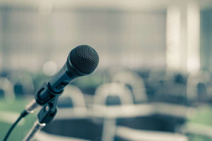 Microphone voice speaker in seminar classroom, lecture hall, town hall meeting or conference forum in educational business event for coaching host or teacher with audiences or students seats