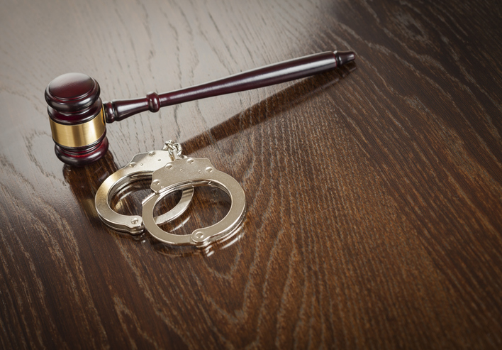 Gavel and pair of handcuffs on wooden table
