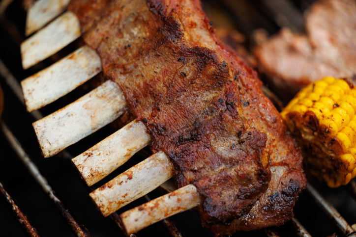 Delicious ribs sizzling on a grill with vibrant corn during a lively summer cookout