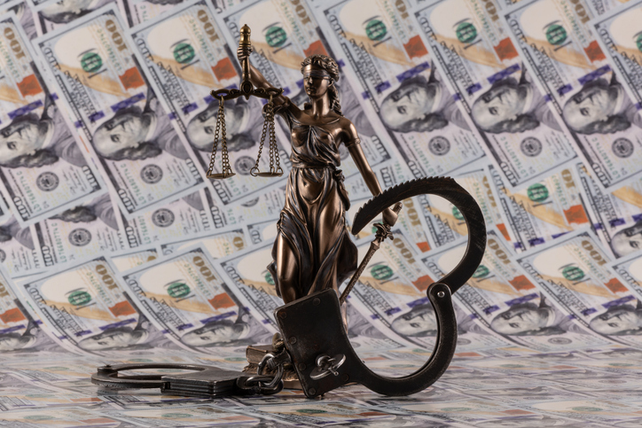 Handcuffs and the figure of Themis against the background of 100 US dollar bills