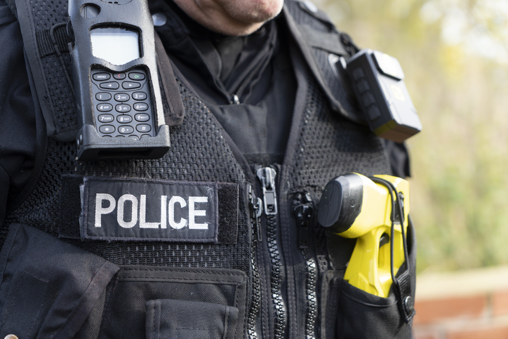 UK police officer with his body camera, taser and police radio attached to his stab vest