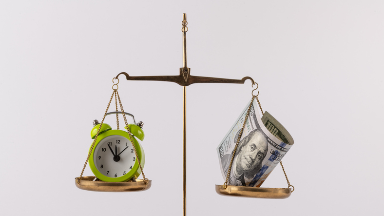 A US$100 bill and an alarm clock on a scale