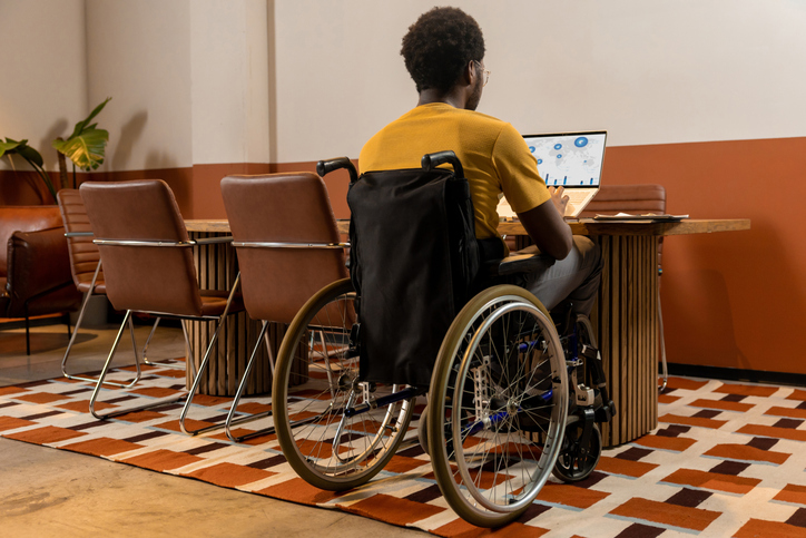 Focused man in wheelchair using laptop working with business data