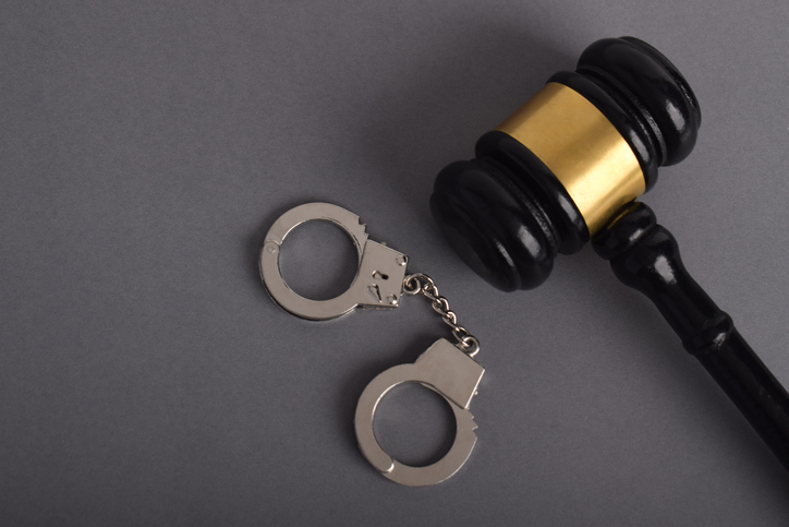 Judge gavel and handcuffs on grey background