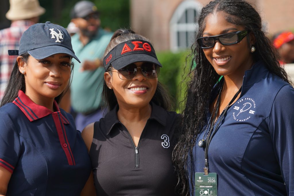 Three young women wearing college sports team apparel and hats, smiling together outdoors.