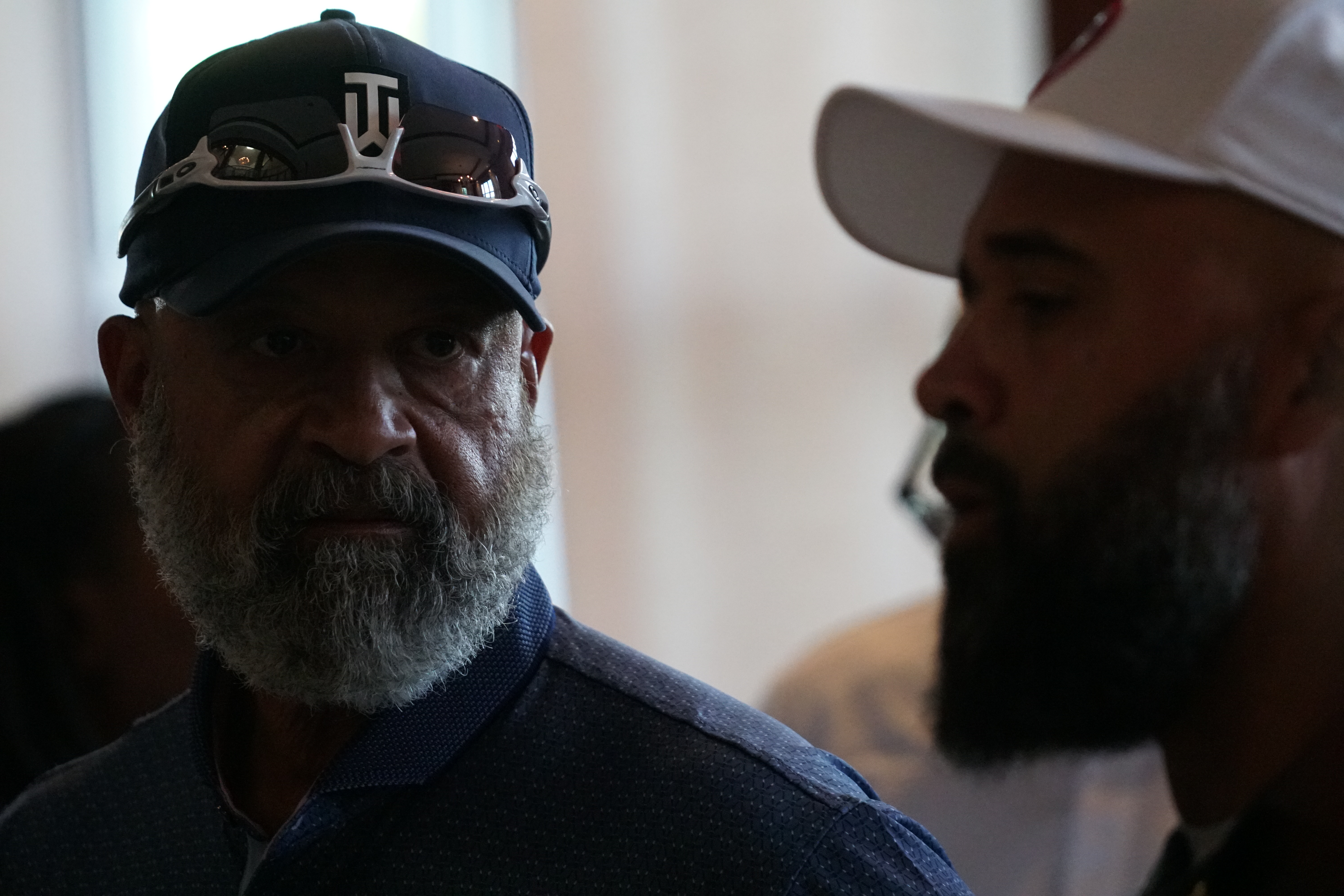 Two men wearing baseball caps and looking at each other intently.