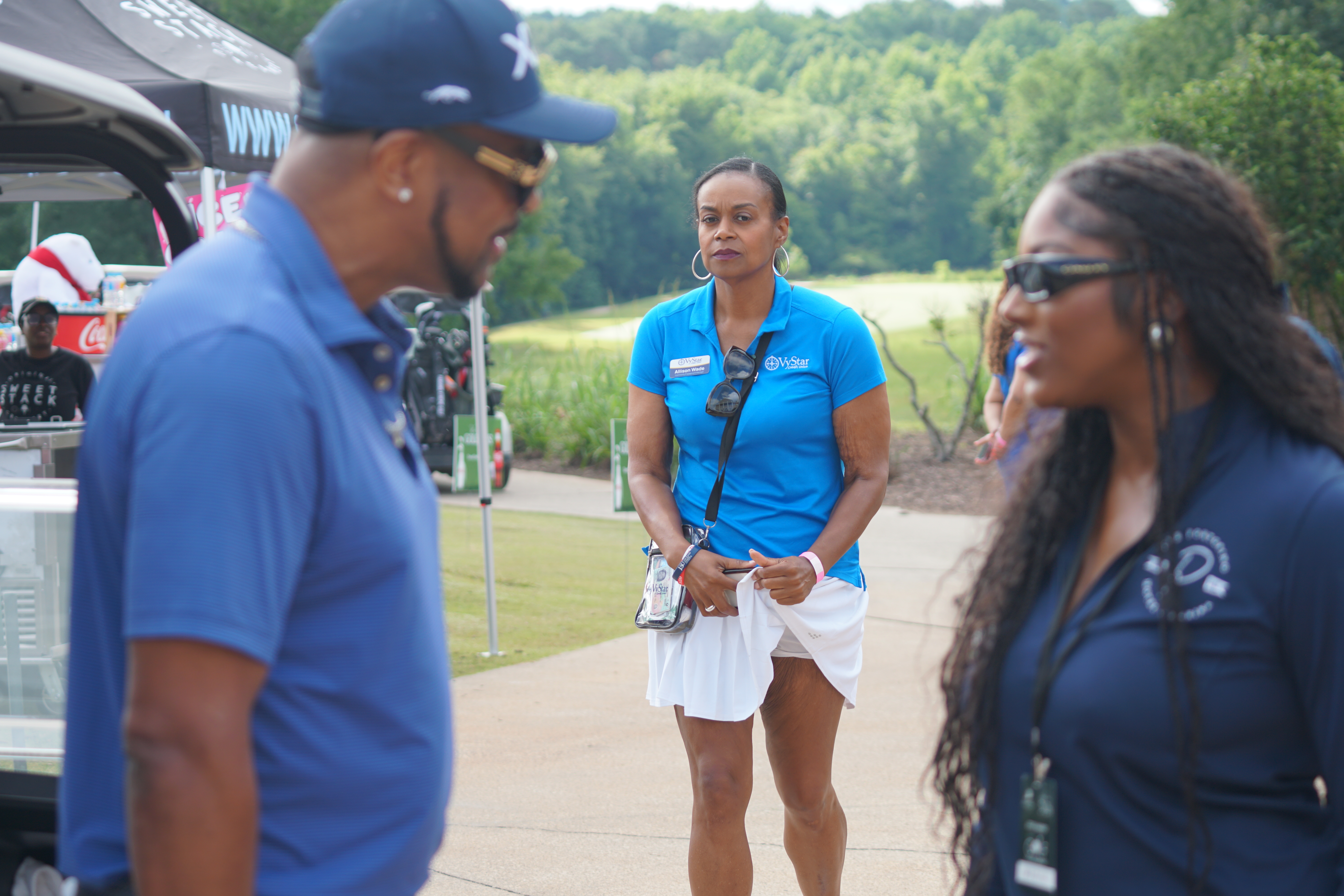 Three people standing outdoors, one wearing a blue Walmart vest and two others in casual clothing.