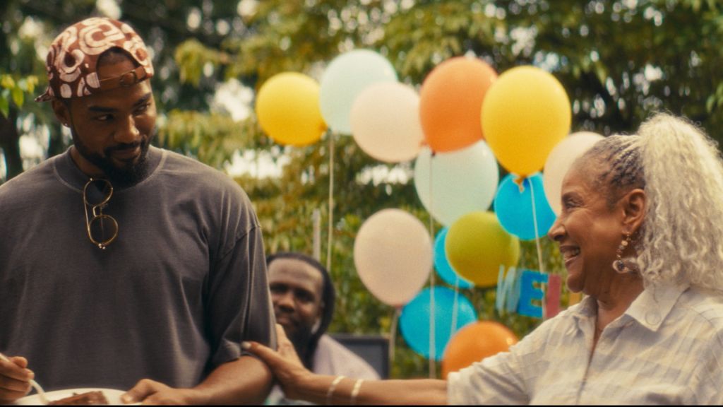 Two people, a man and a woman, standing in a park surrounded by colorful balloons.