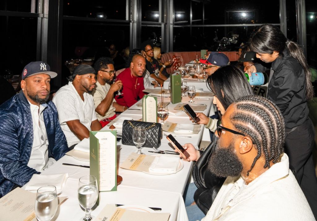 A group of people gathered around a table at a restaurant, engaged in conversation and enjoying drinks.