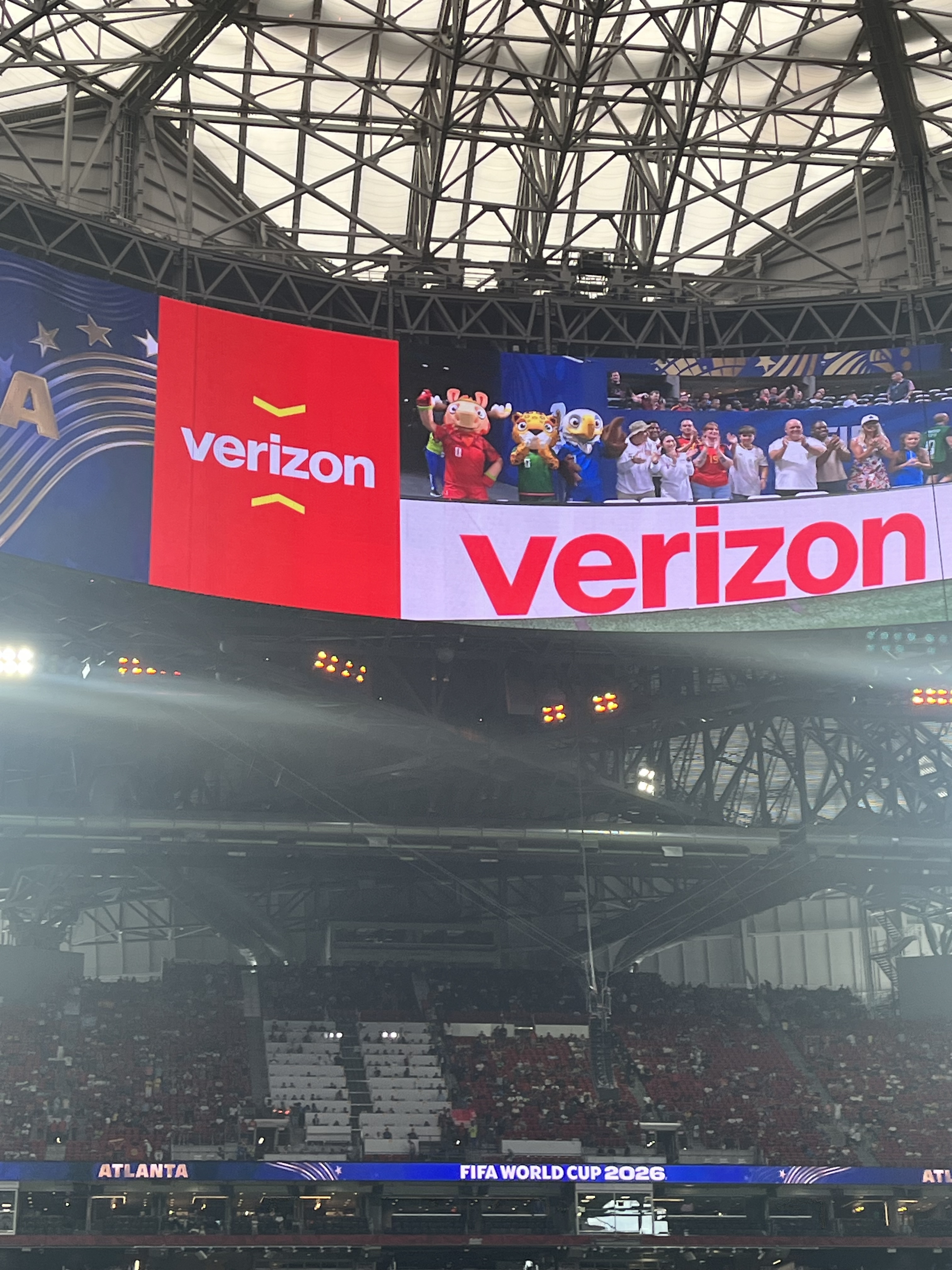 Large indoor arena with Verizon branding and mascots on the field during the 2026 FIFA World Cup event in Atlanta.