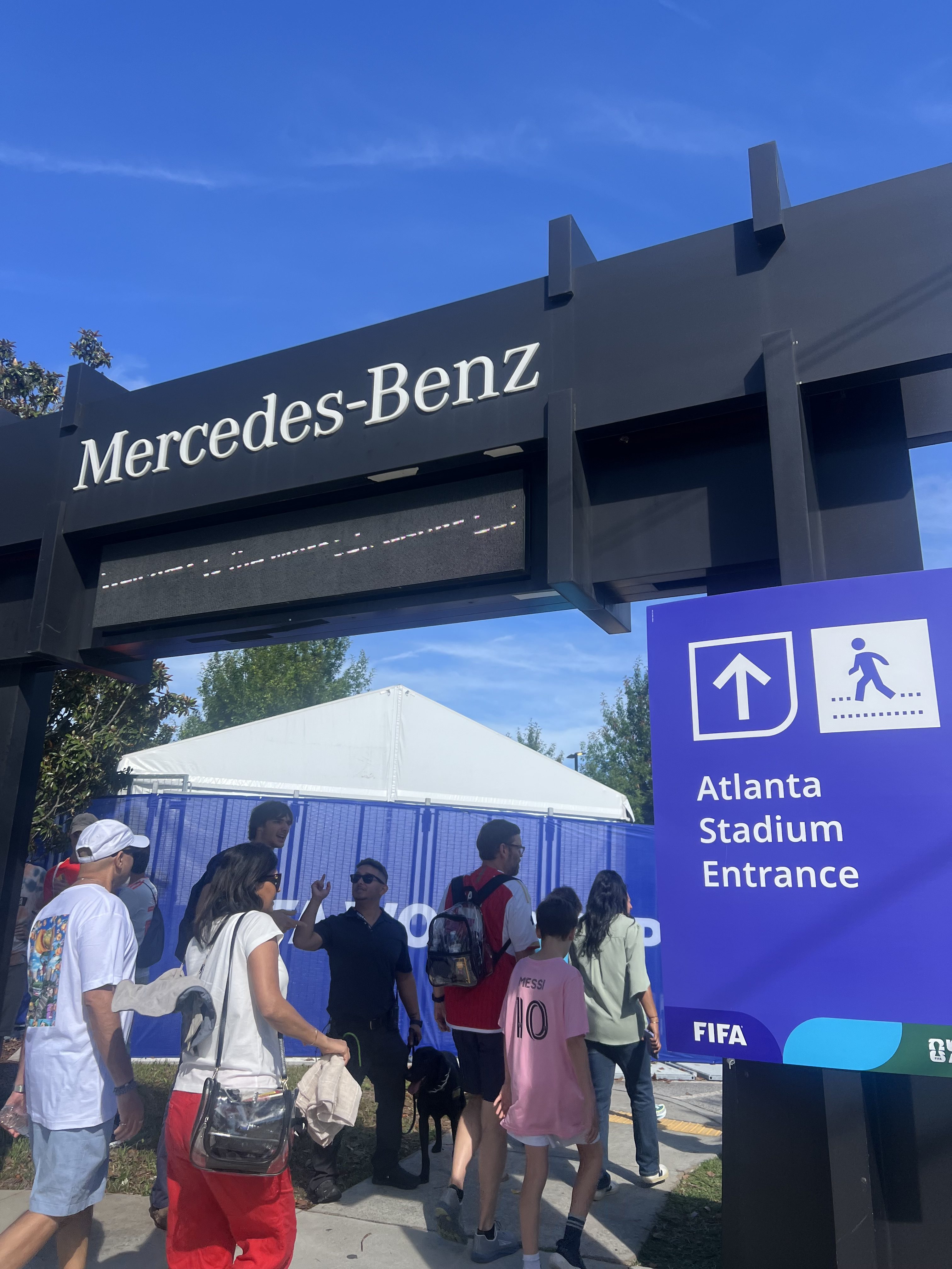 Mercedes-Benz sign above entrance to Atlanta Stadium, with people walking towards the entrance.