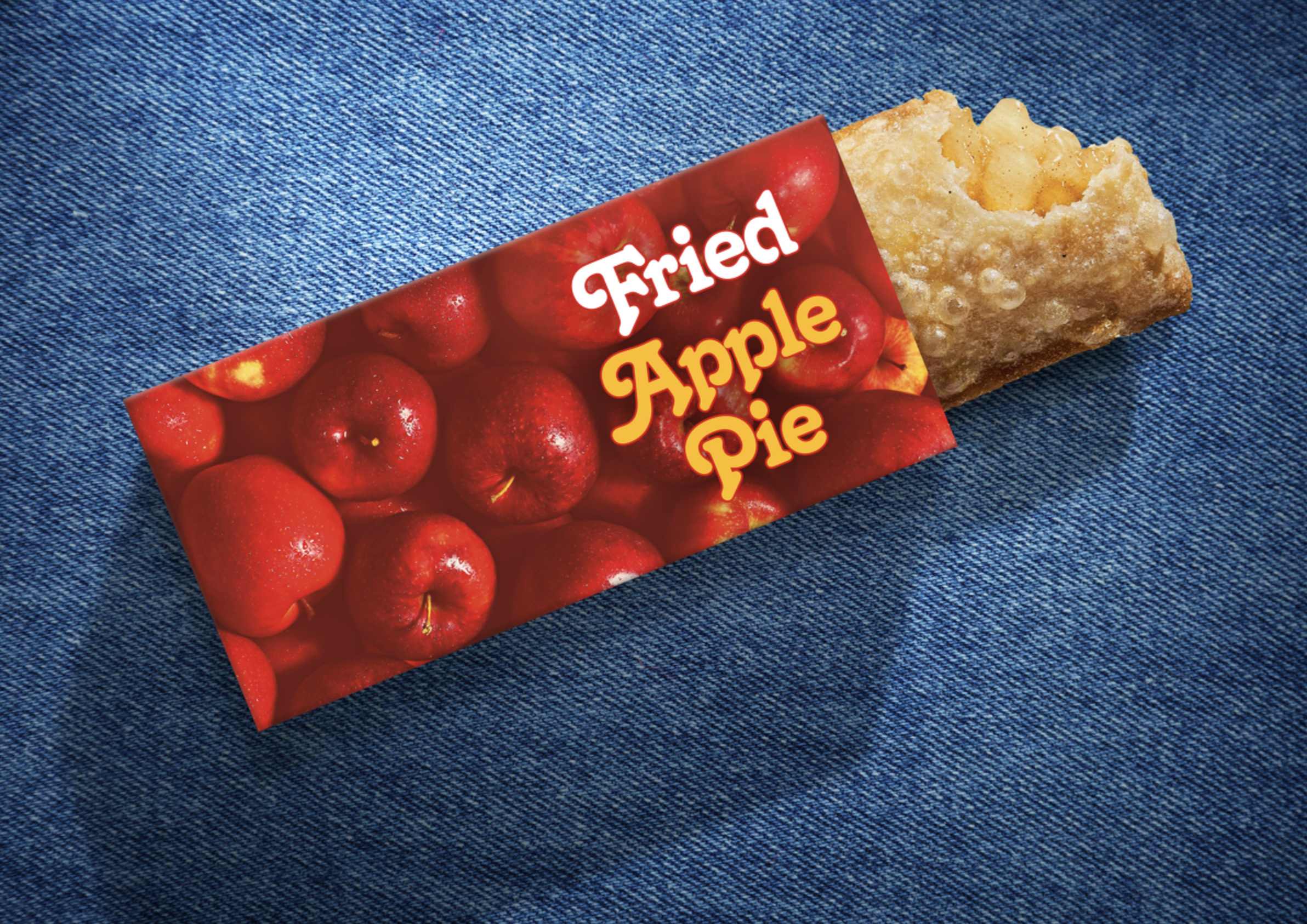 Fried Apple Pie package with red apples and a piece of fried pastry on a denim background.