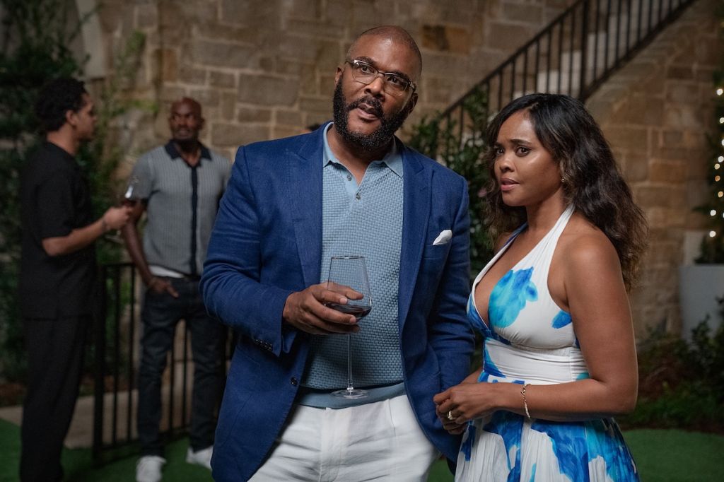 Two people, a man in a blue suit and a woman in a patterned dress, standing together outdoors at night.