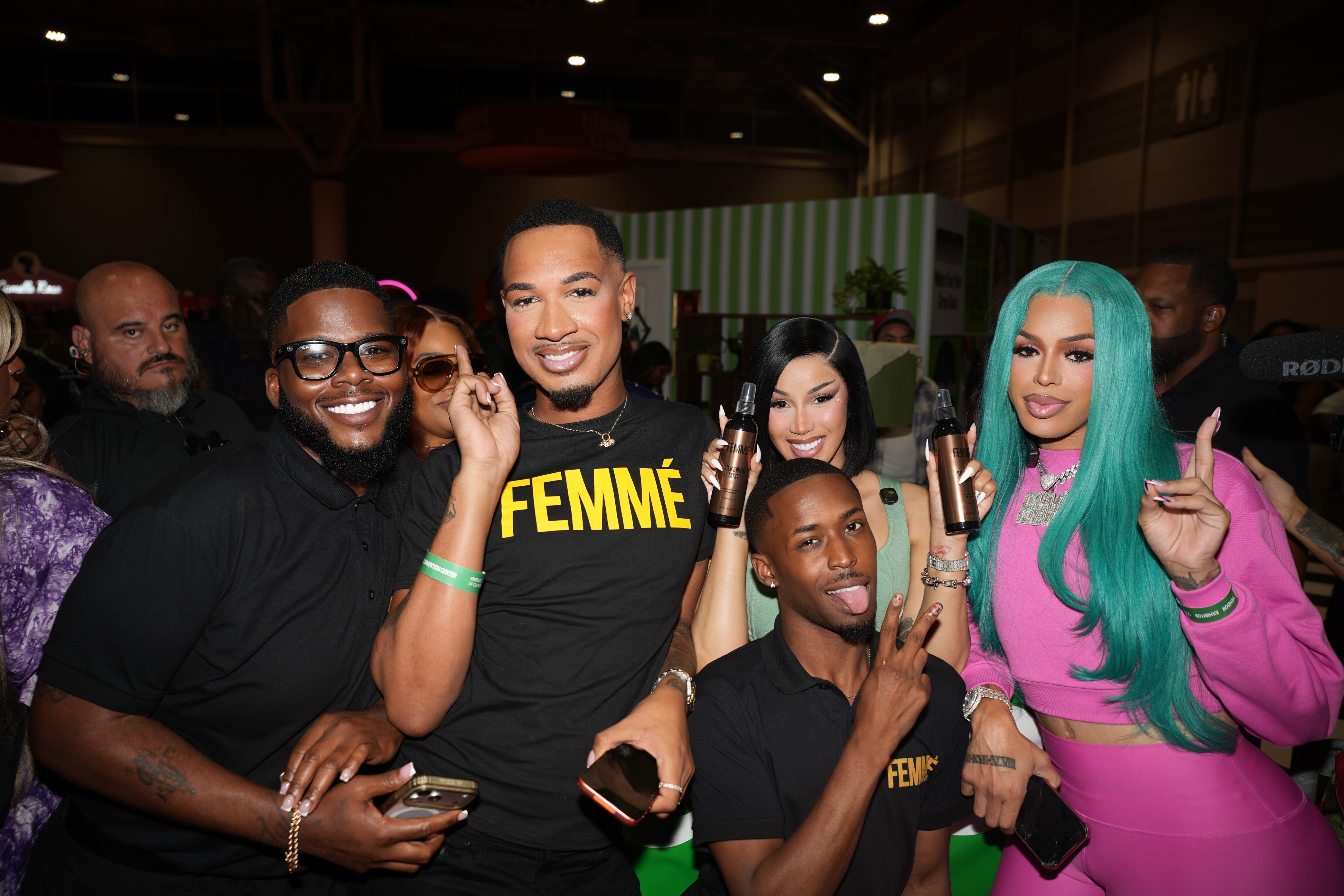 A group of people posing together, wearing clothing with the word "FEMME" printed on it, and making various hand gestures.