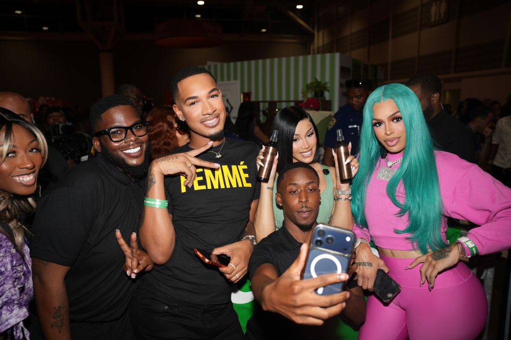 A group of people, including a person wearing a "PEMME" t-shirt, posing for a selfie at what appears to be an event or gathering.