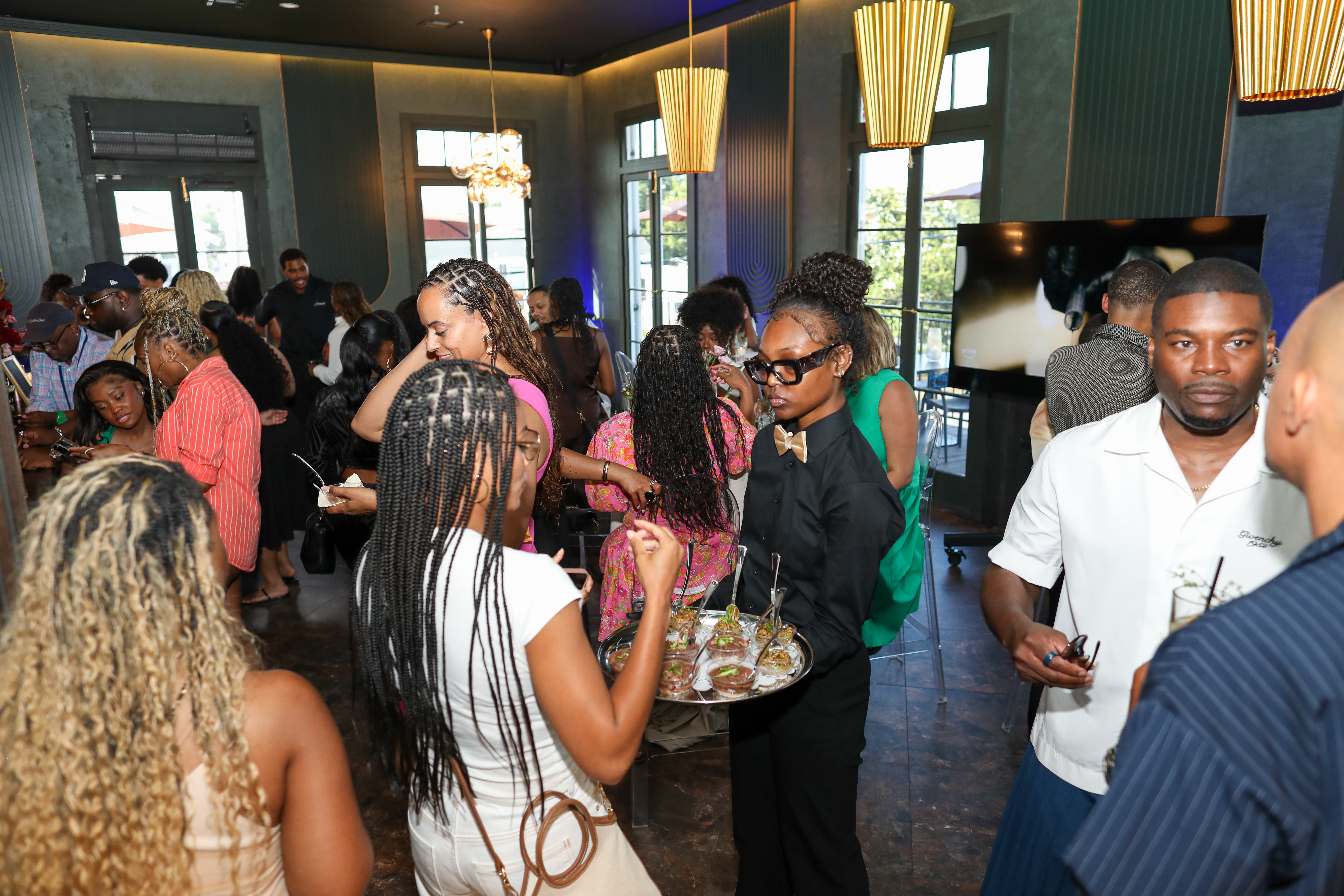 A crowded indoor gathering with many people, some wearing formal attire, enjoying food and drinks.