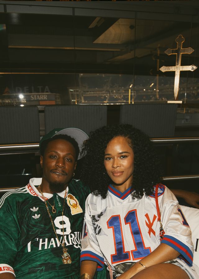 Two people, a man and a woman, wearing sports jerseys posing in front of a cross and other religious symbols.