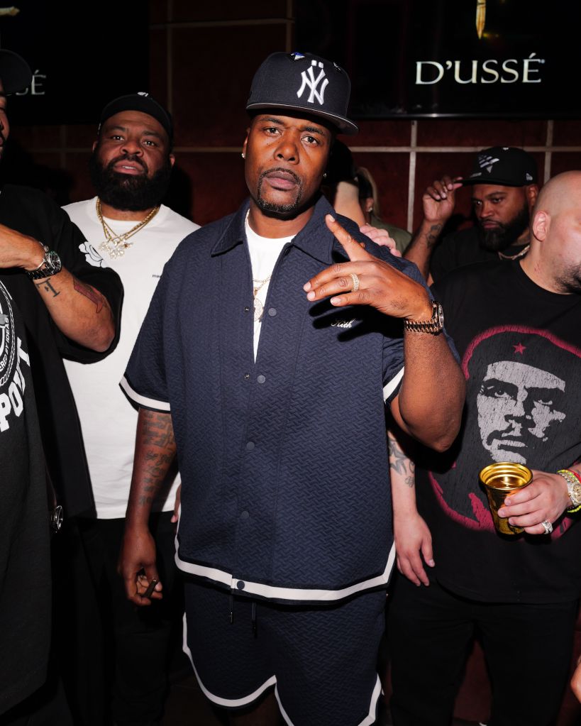 Three men wearing New York Yankees baseball caps and casual clothing standing together in a bar or club setting.