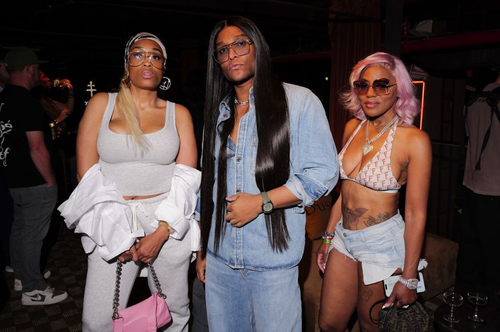 Three people posing together in casual clothing, with one person wearing a denim jacket and the other two wearing crop tops and shorts.