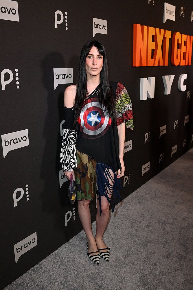 A woman wearing a Captain America-themed outfit stands in front of Bravo network branding at an event.