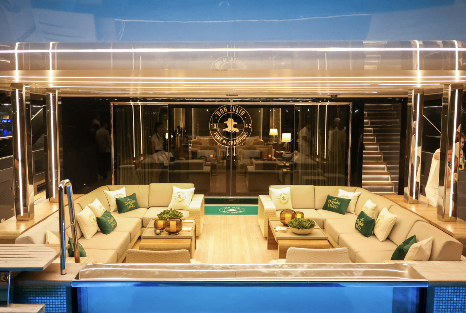 Luxurious lounge area with plush beige sofas, wooden tables, and decorative accents. The space features the "Don Julio" logo, indicating a high-end establishment.