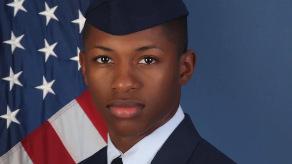 Portrait of a young man in military uniform with an American flag in the background.