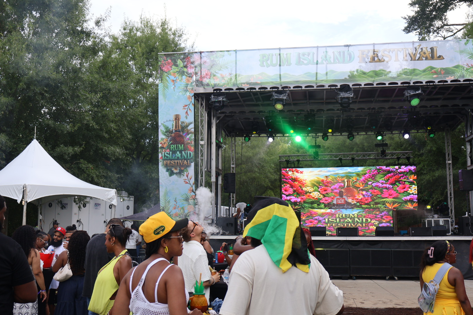 Outdoor music festival with colorful stage, tents, and crowd enjoying the Rum Island Festival event.