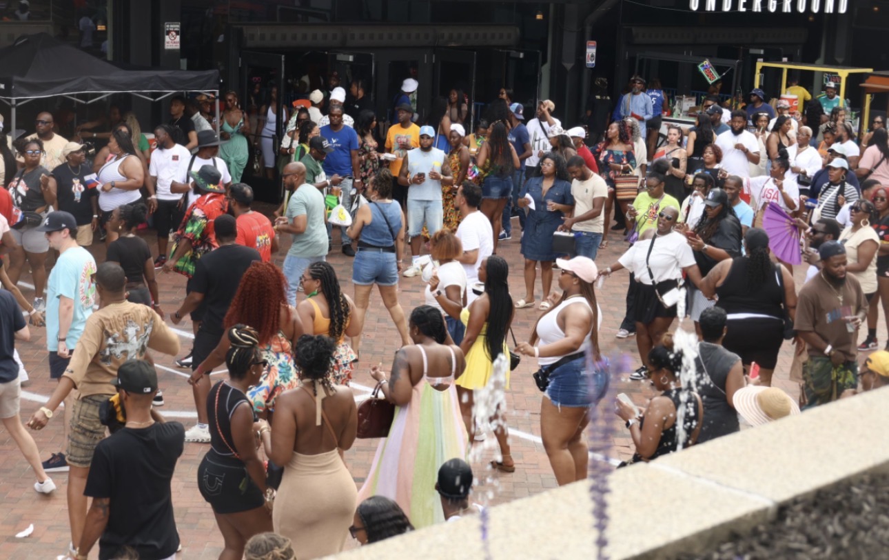 Crowded urban nightlife scene with people dancing and socializing in an outdoor public space.