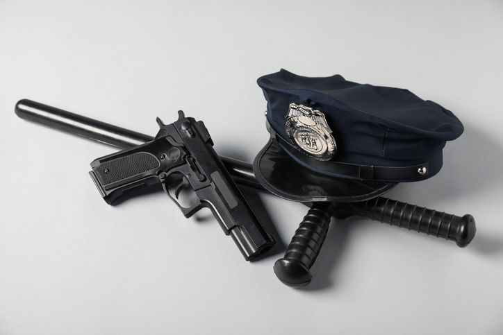Police cap, gun and baton on white background