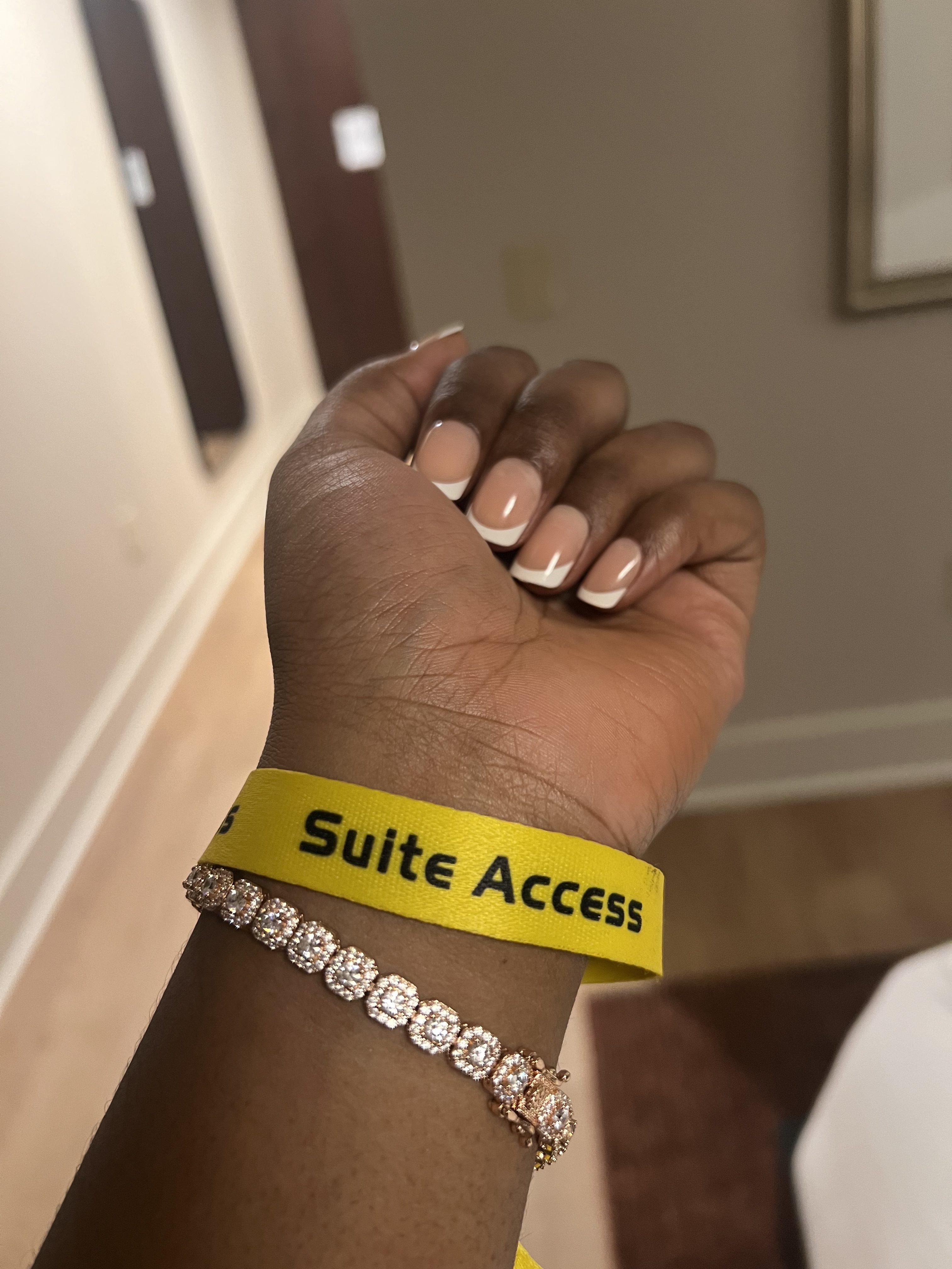 A hand wearing a bracelet with the text "Suite Access" on a yellow wristband.