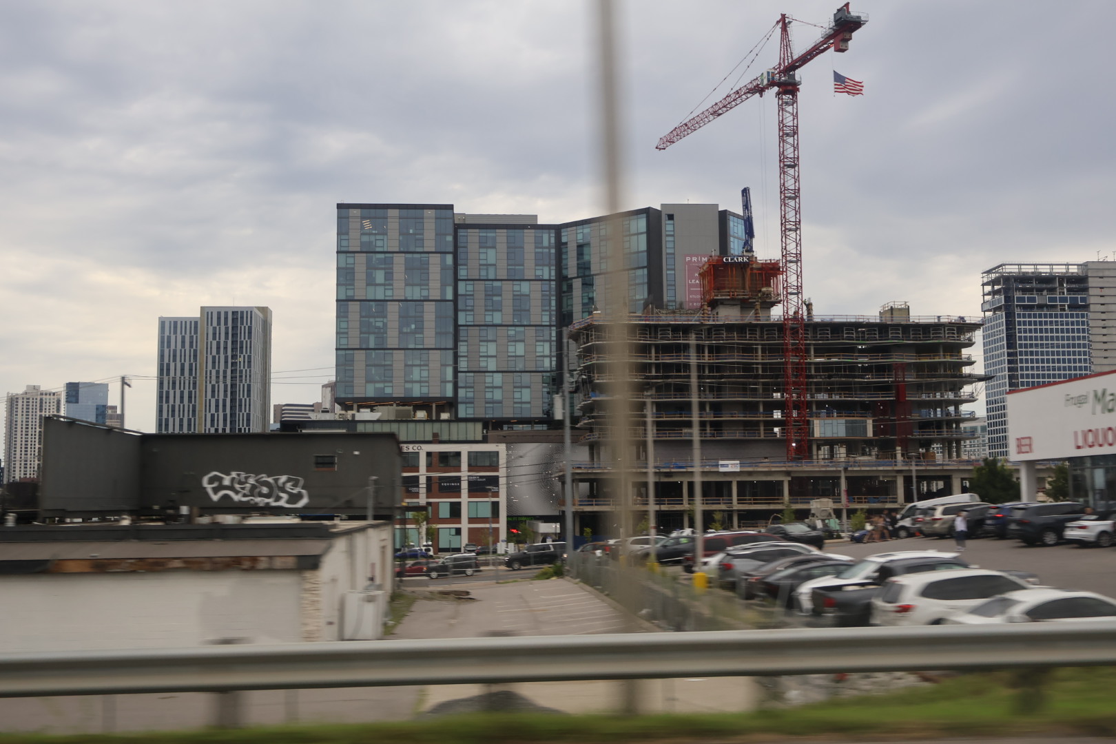 Cityscape with high-rise buildings under construction, including a crane and American flag.