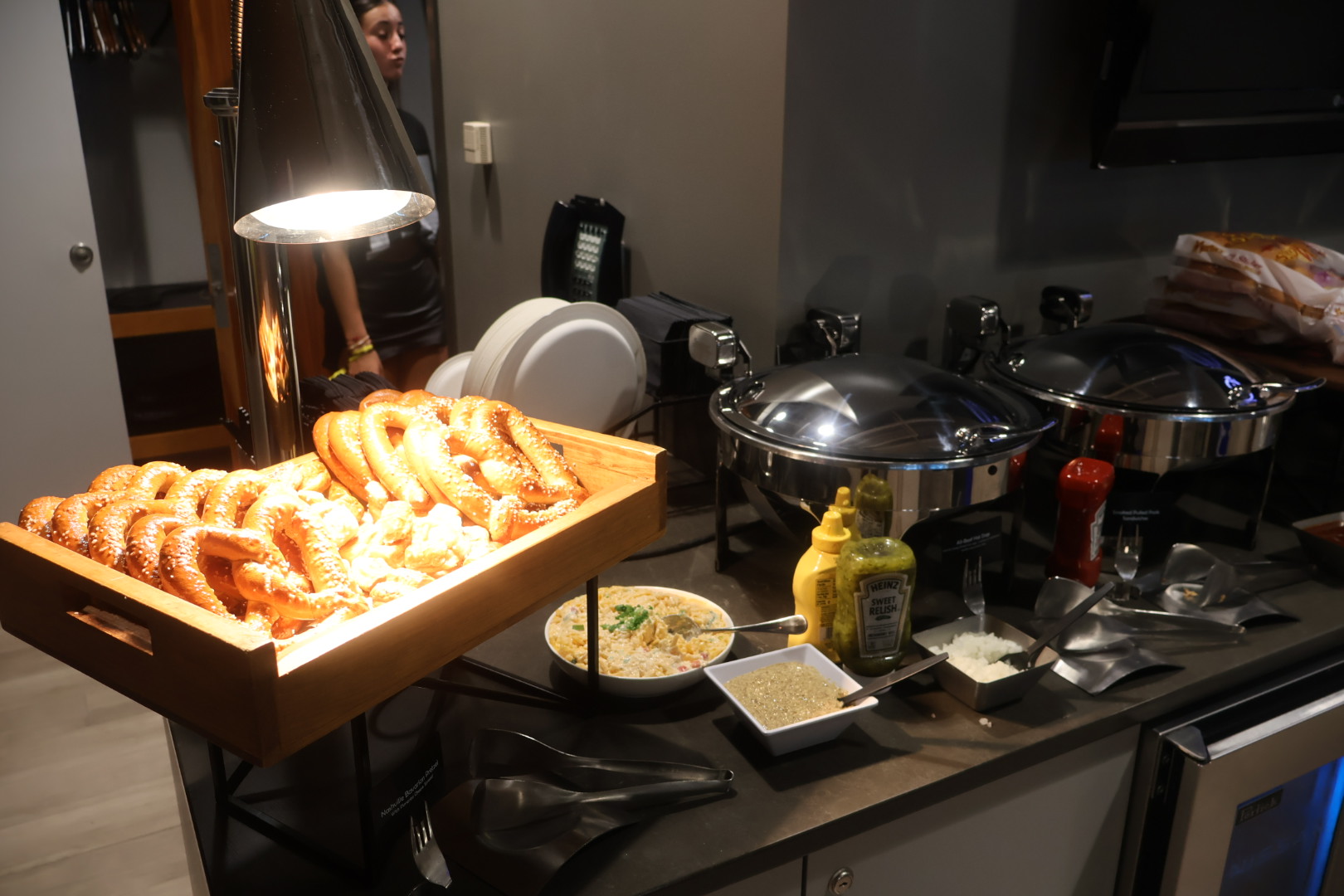 A kitchen counter with various cooking appliances, utensils, and a tray of freshly baked pretzels.
