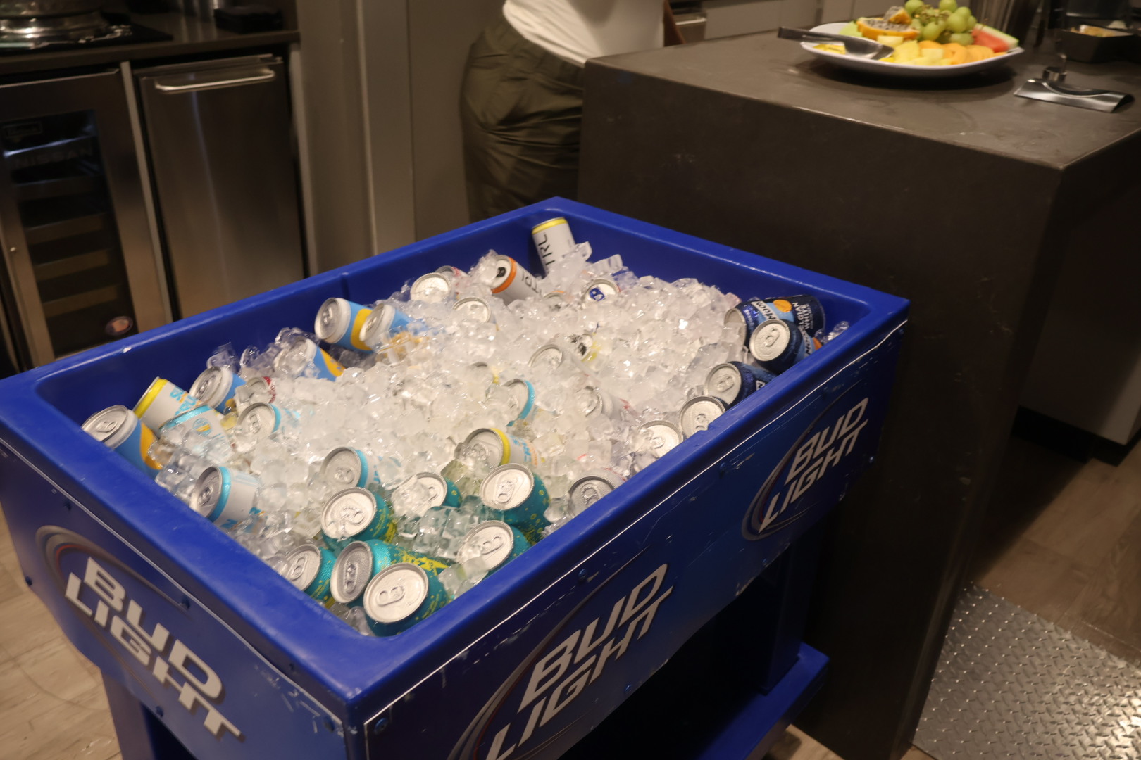 A blue plastic container filled with crushed ice and various beverage cans.