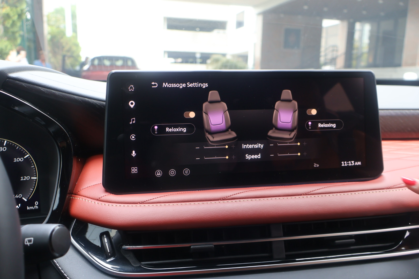 The image shows the interior of a vehicle, with a touchscreen display showing massage settings for the seats, including options to adjust the intensity and speed of the massage.