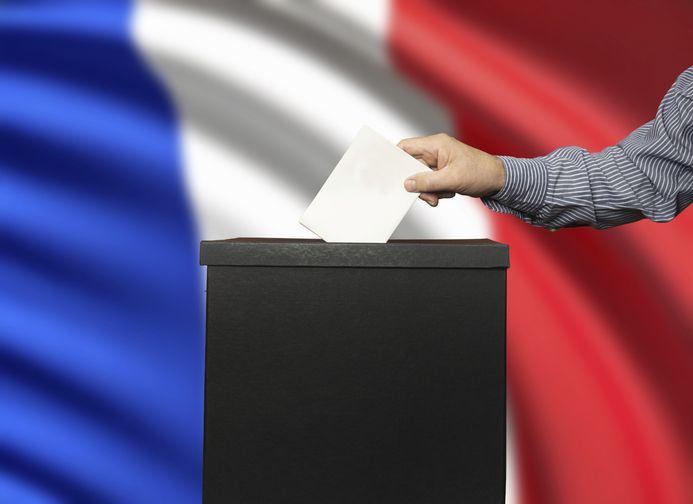 The gesture of placing the ballot in the ballot box with the french flag in the background