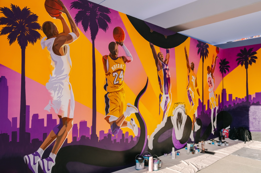 Vibrant mural depicting basketball players in action against a cityscape backdrop with palm trees and a purple and orange sky.