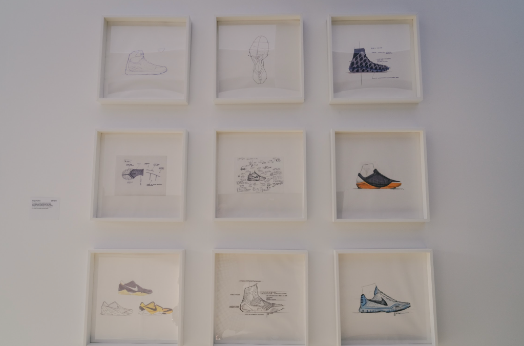 Nine framed sketches of various shoe designs displayed on a white wall.