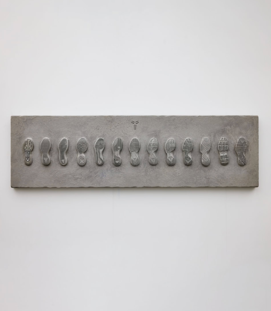 A concrete slab with impressions of various shoe soles, representing a collection of footprints.