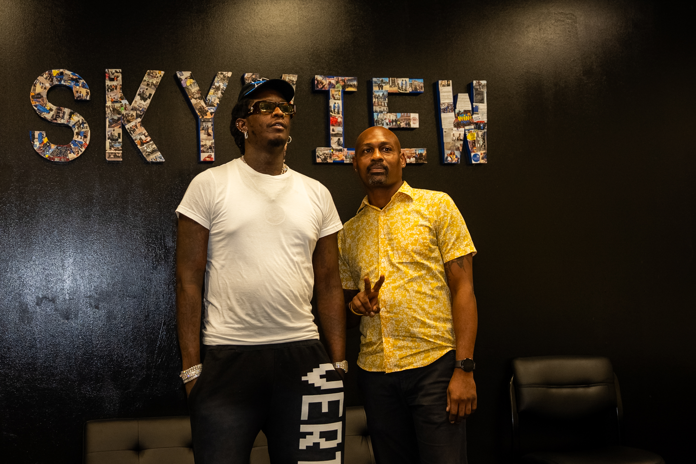 Two men standing in front of a wall with the word "Skytel" displayed prominently.