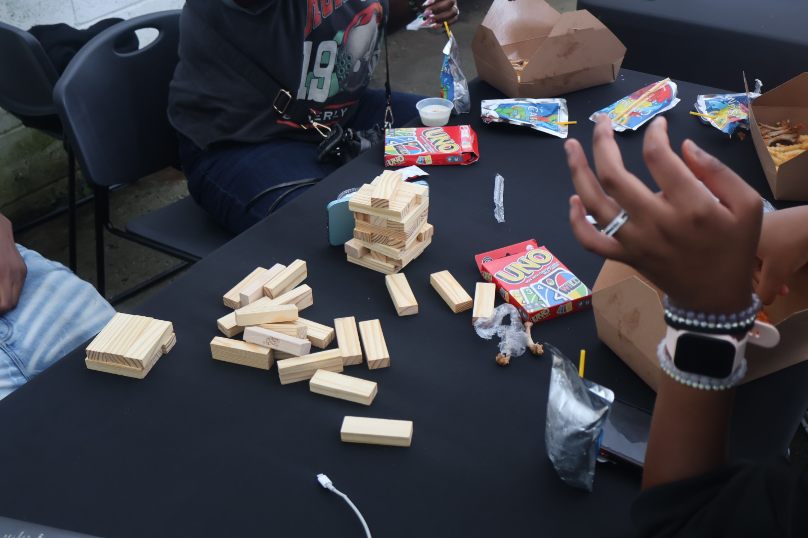 A table with various snacks and a wooden game piece, along with a person's hands visible.