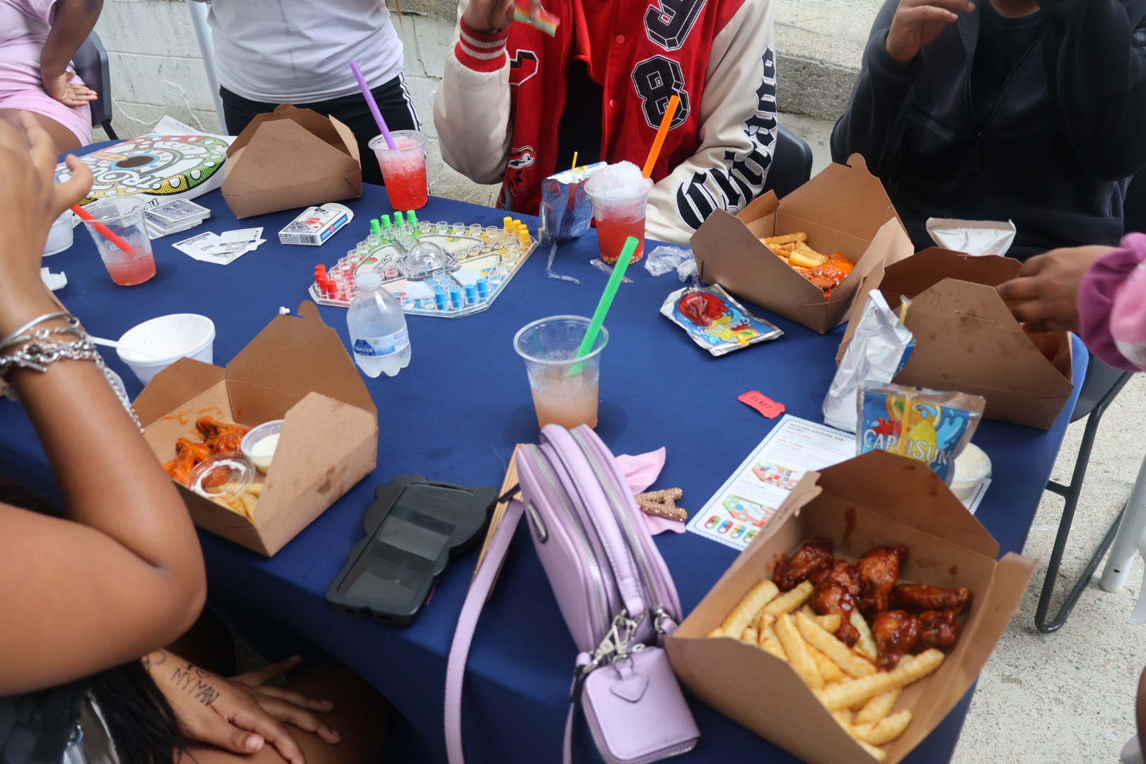 A table with various fast food items, drinks, and personal belongings, including a red jersey with the number 28.