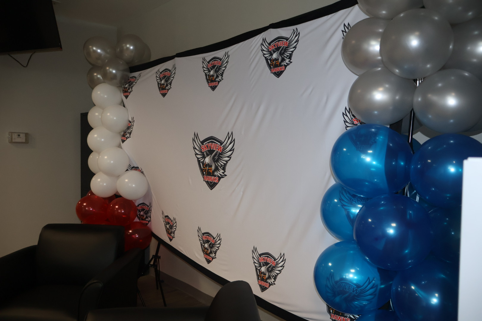 A room decorated with white balloons, silver balloons, and a white banner featuring the logo of the Samurai Esports team.