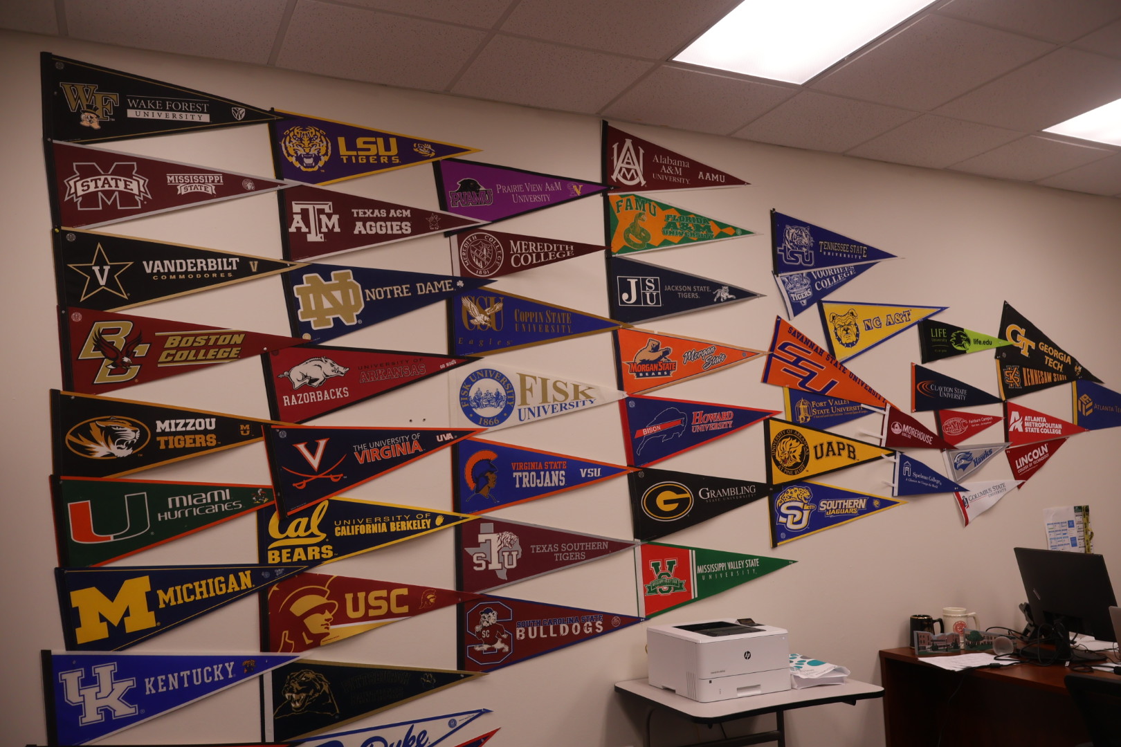Wall display of college sports team pennants and logos.