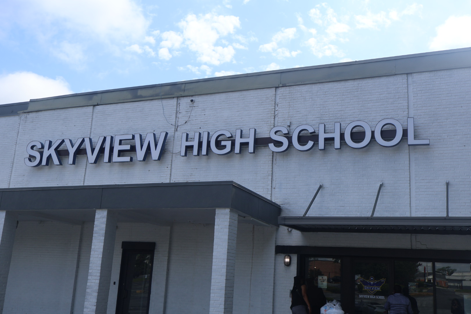 Skyview High School building exterior with large text signage on the facade against a cloudy sky.
