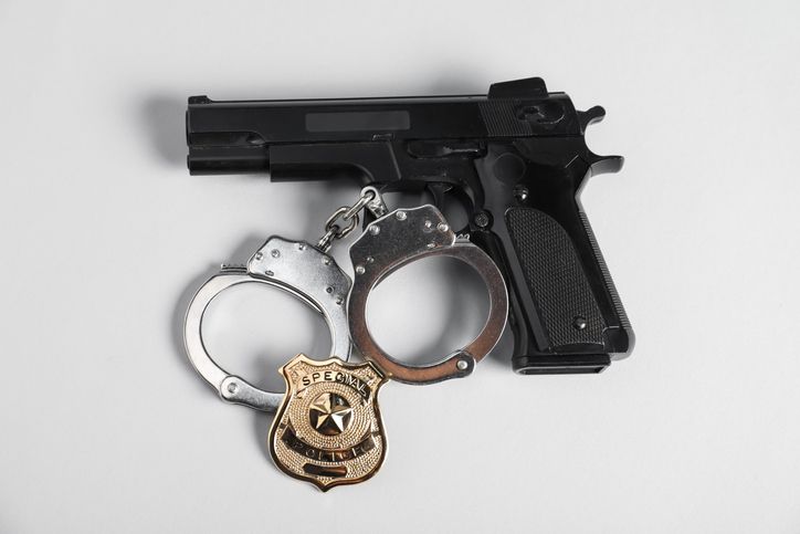 Police badge, gun and handcuffs on white background, above view